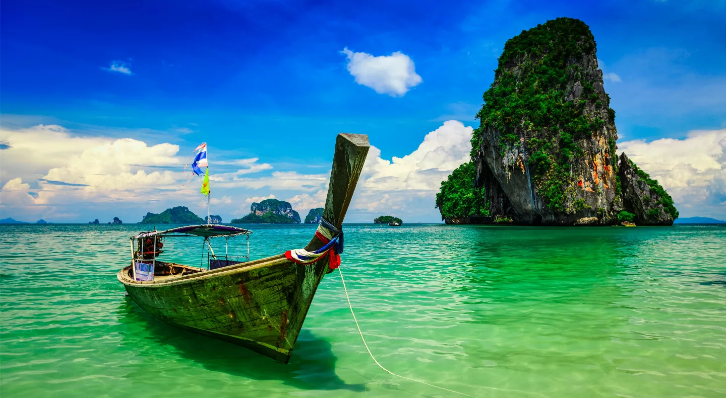 Longtail-Boot auf türkisfarbenem Wasser vor Thailands Inselküste.